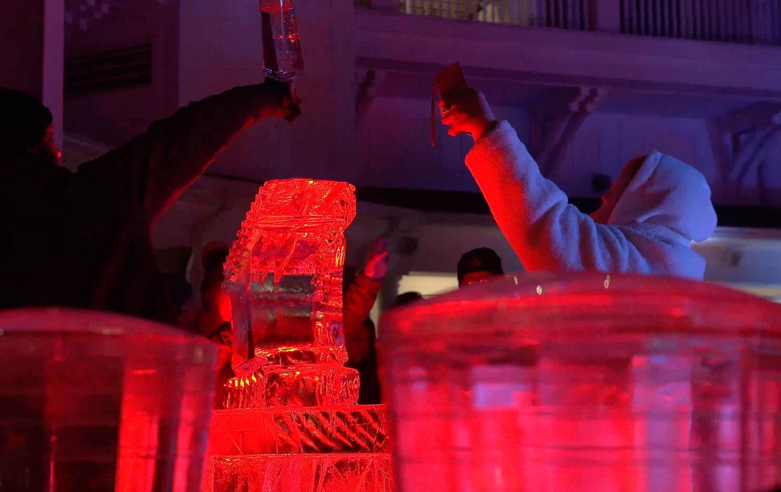 Multiple guests at the Fire and Ice celebration drinking from the ice luge