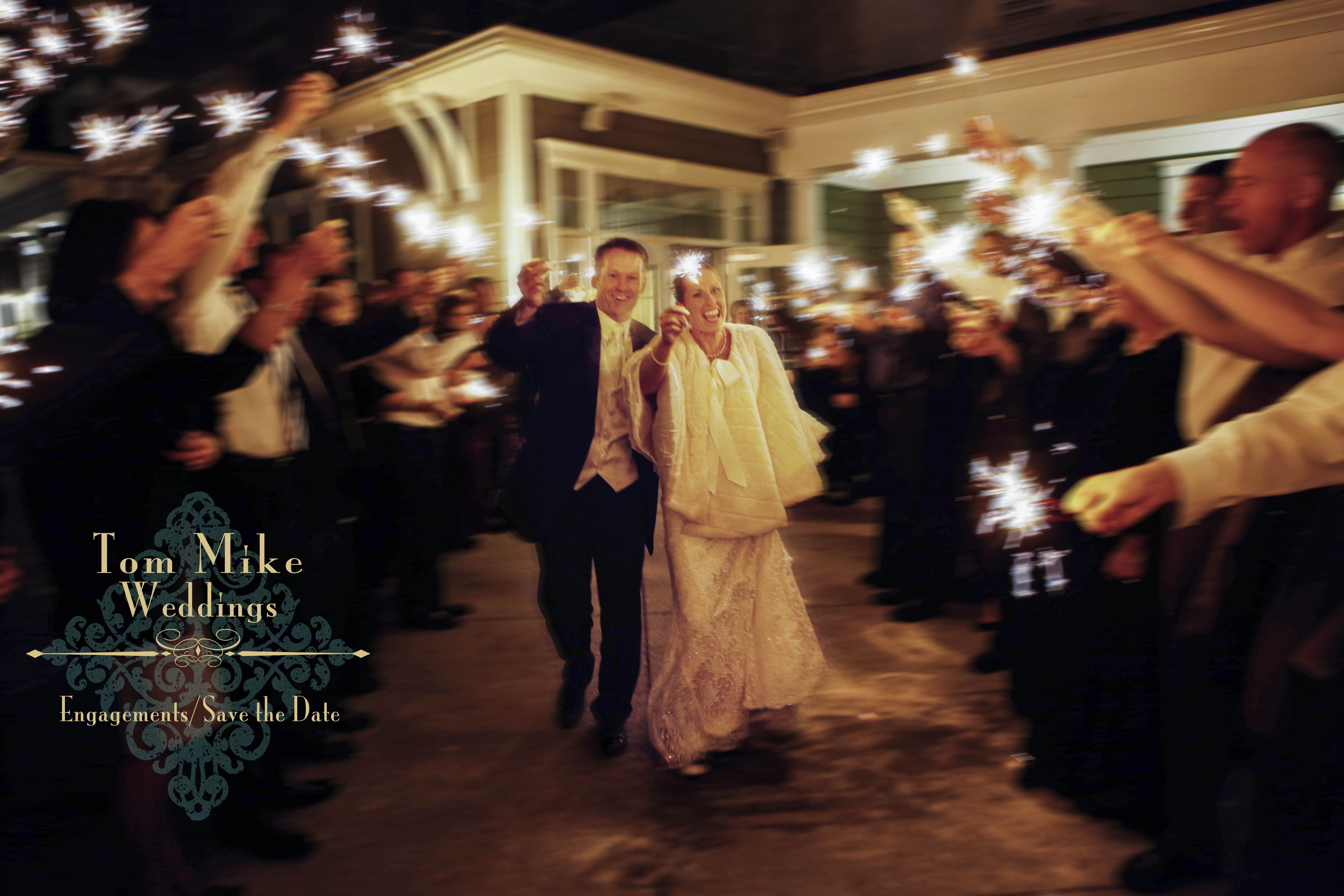 A bride and groom exit their ceremony with sparklers alight