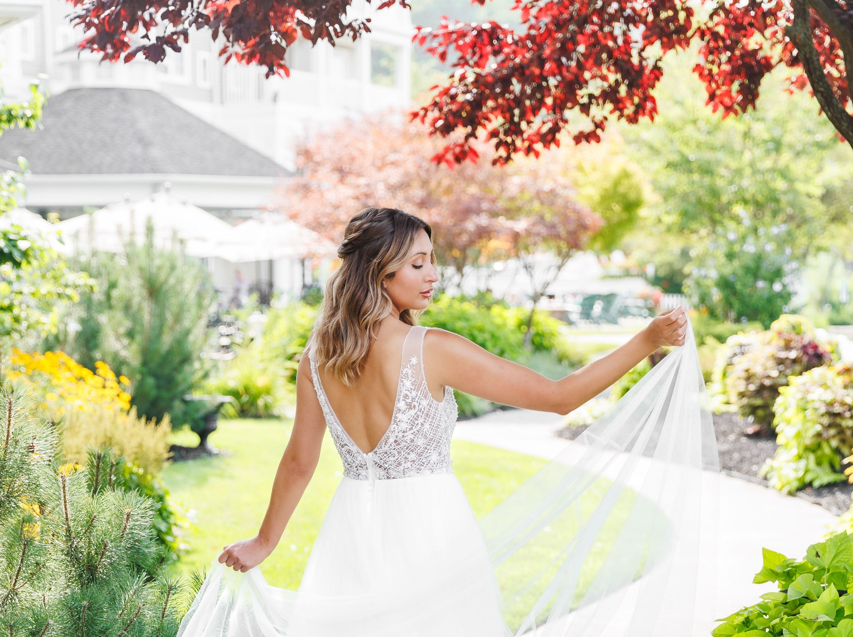 A bride shows off her beautiful dress while walking down the path outside the Watkins Glen Harbor Hotel