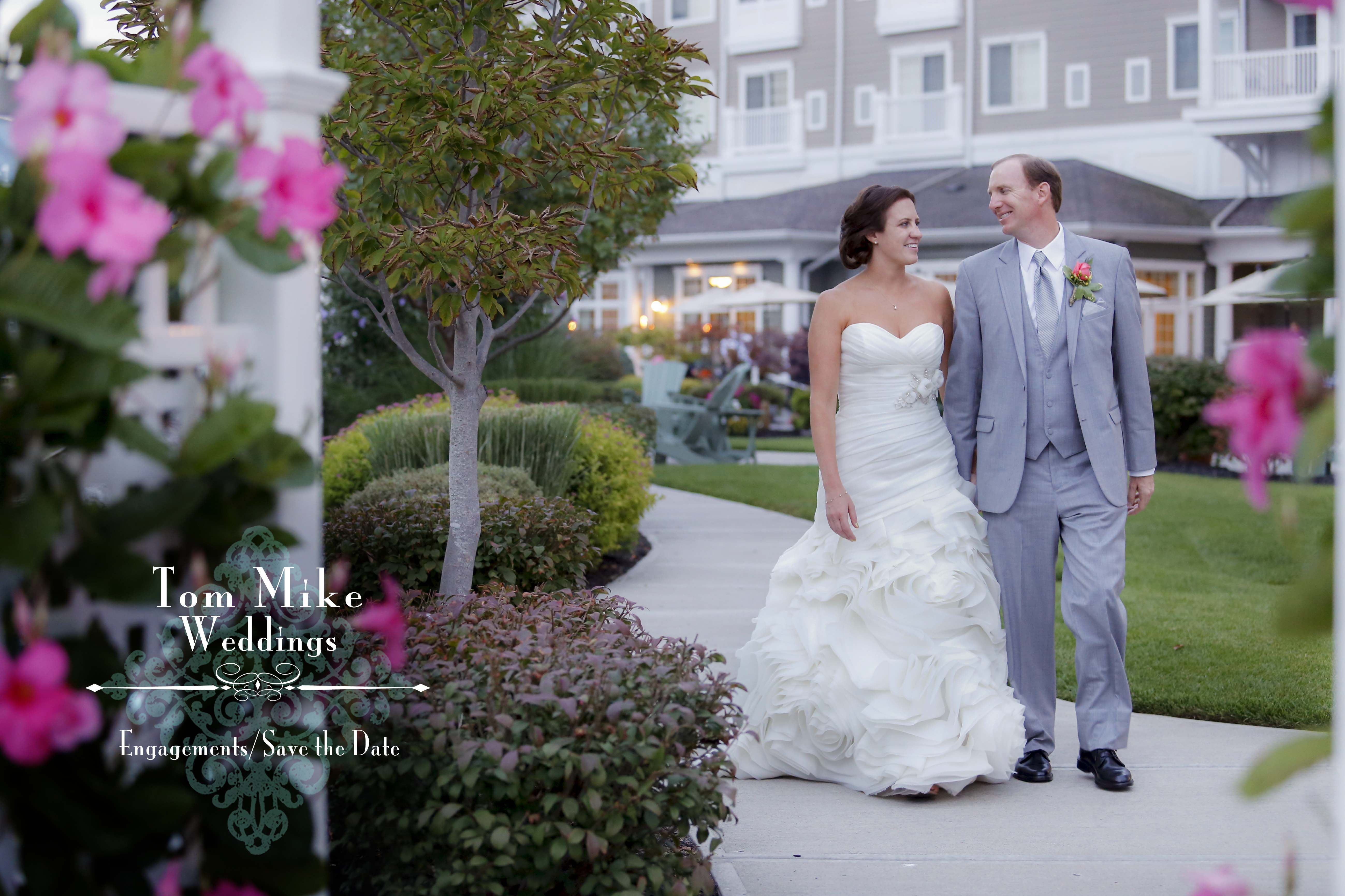 A bride and groom walking on the patio with floral arbor