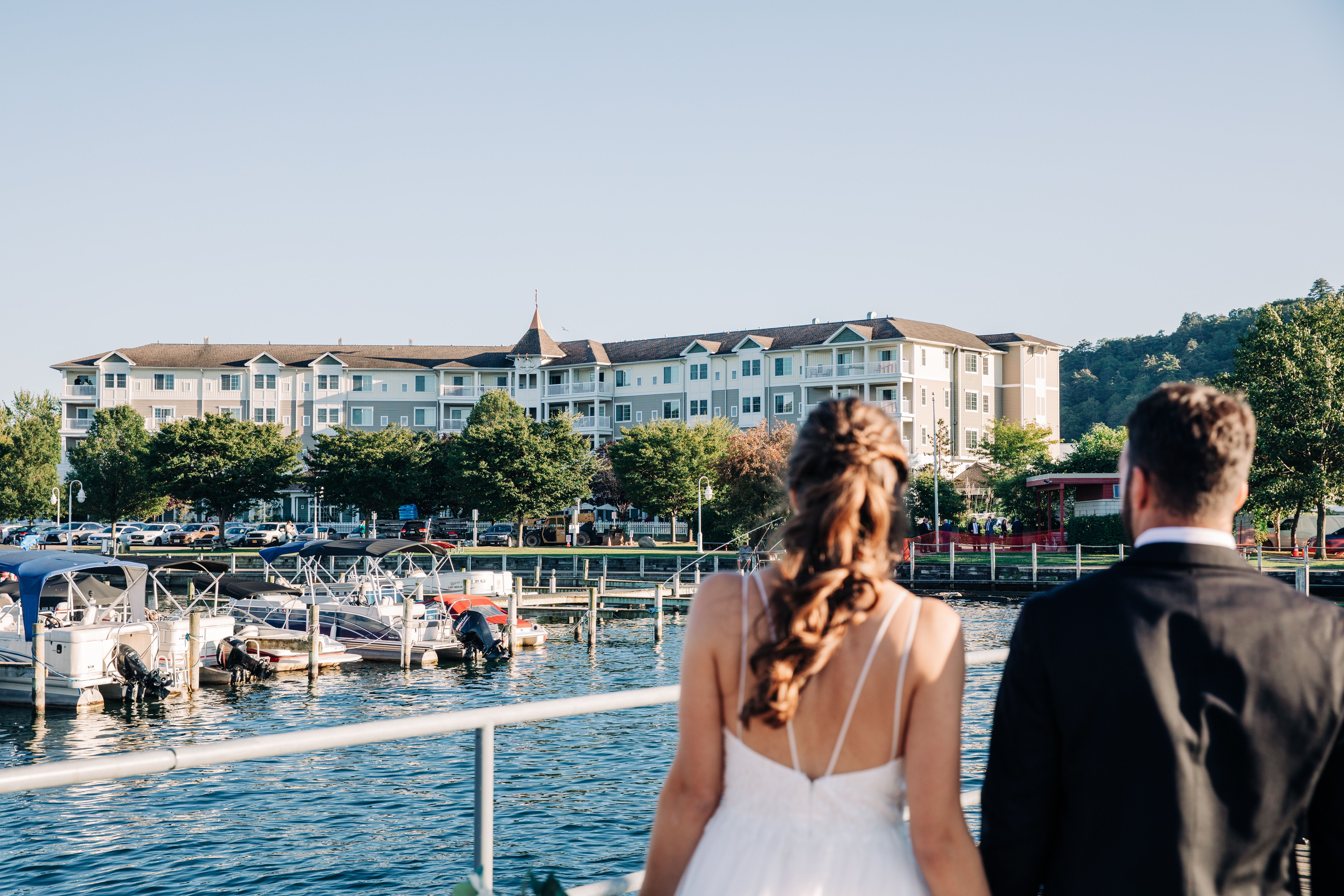 A bride and groom look towards the Watkins Glen Harbor Hotel from the Seneca Lake Pier