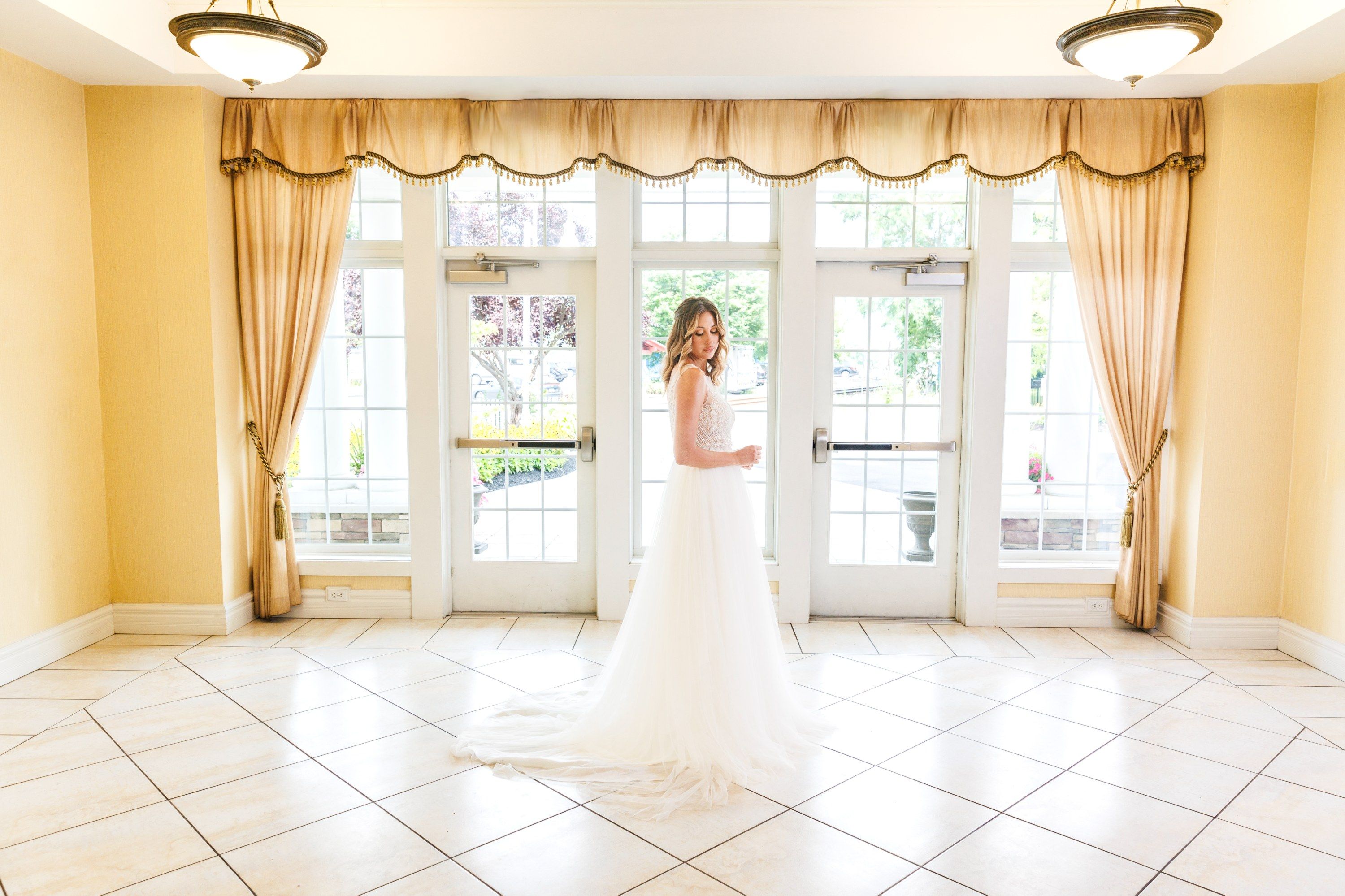 A bride shows off her beautiful dress while standing in the ballroom foyer at the Watkins Glen Harbor Hotel